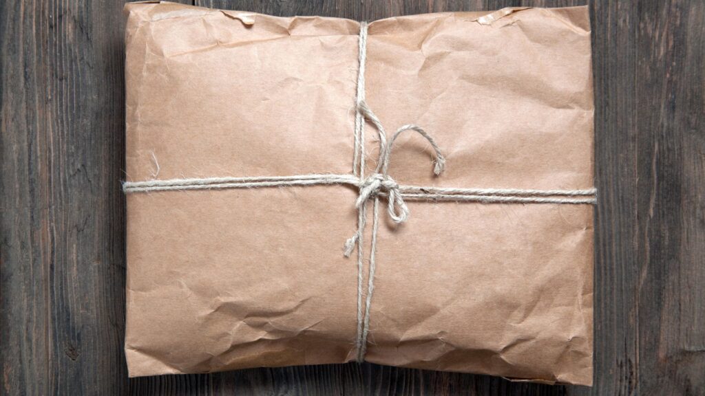 In braunes Papier eingeschlagenes Paket mit Schnur auf einem Holztisch